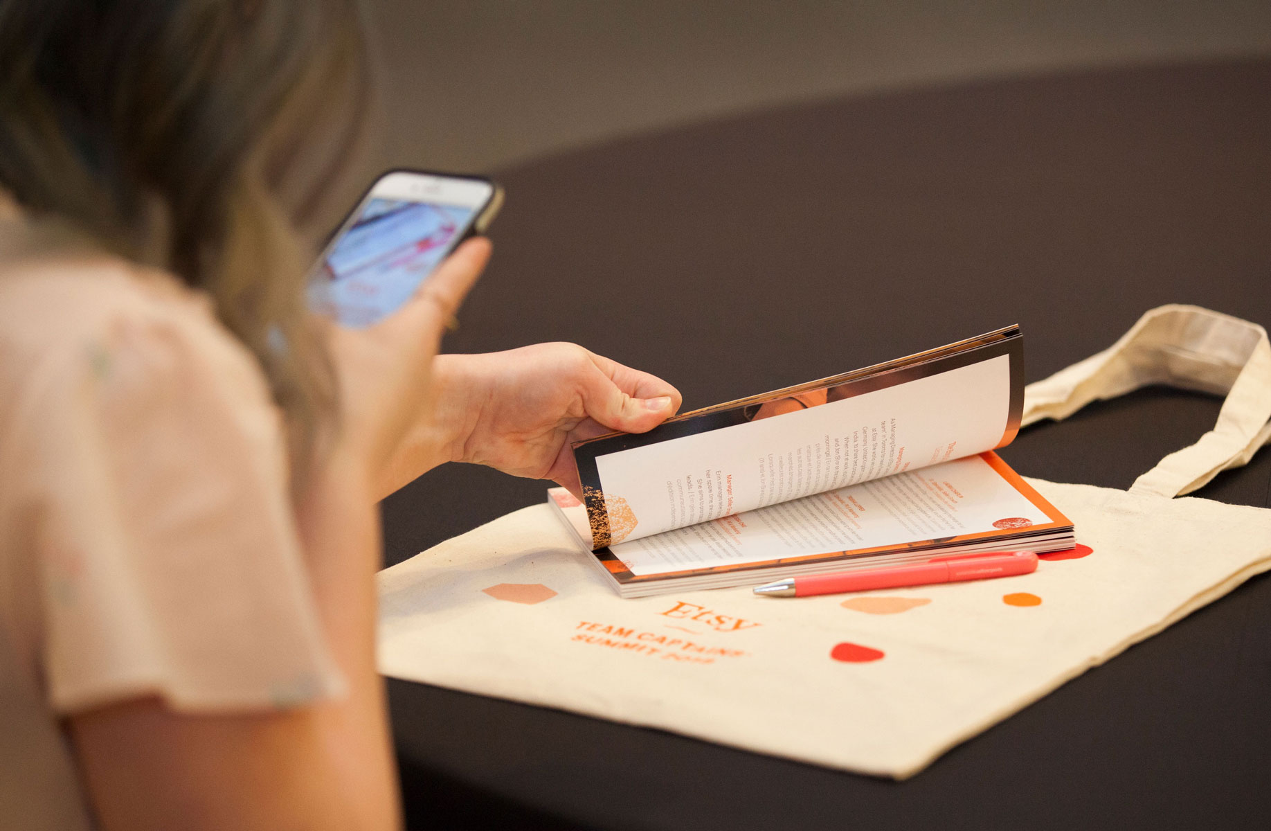 An attendee at the Etsy Captains' Summit takes a photo of their swag with their phone